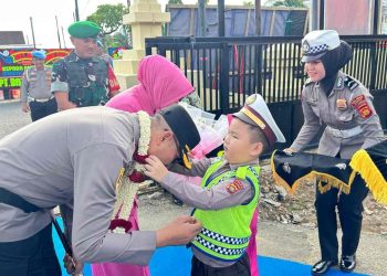 TRADISI : Polisi cilik mengalungkan bunga kepada Kapolres Bungo Zamri Elfino saat tiba di Mapolres Bungo dalam rangkaian tradisi penyambutan Kapolres baru