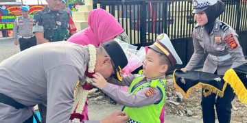 TRADISI : Polisi cilik mengalungkan bunga kepada Kapolres Bungo Zamri Elfino saat tiba di Mapolres Bungo dalam rangkaian tradisi penyambutan Kapolres baru