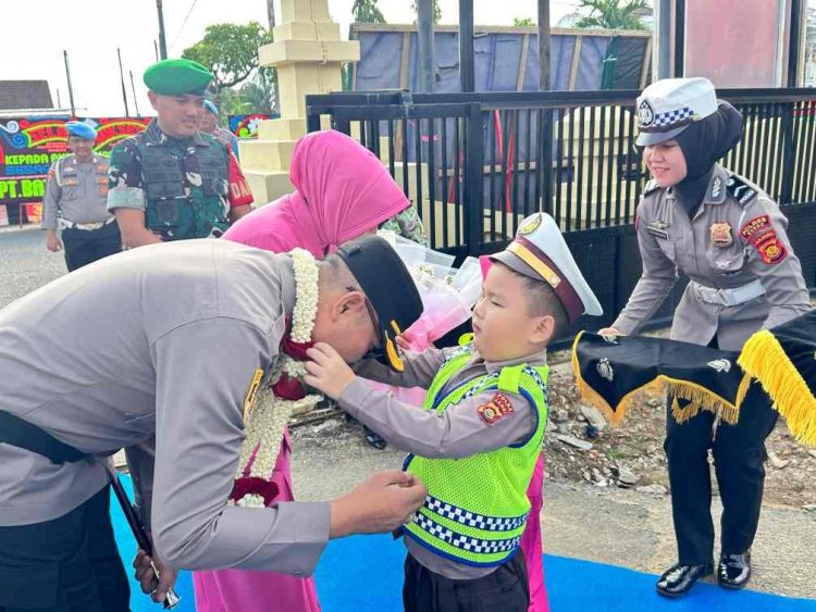 TRADISI : Polisi cilik mengalungkan bunga kepada Kapolres Bungo Zamri Elfino saat tiba di Mapolres Bungo dalam rangkaian tradisi penyambutan Kapolres baru