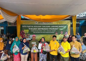 PASAR MUARAH : Ketua DPD Golkar Tanjab Barat, Syufrayogi Syaiful, menyerahkan paket sembako kepada warga dalam kegiatan pasar murah di Kuala Tungkal